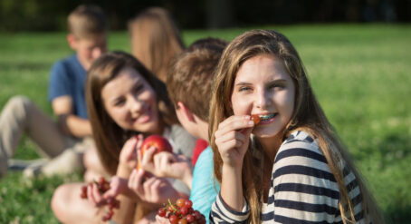 Teenager wearing braces, looking at the camera while eating a grape