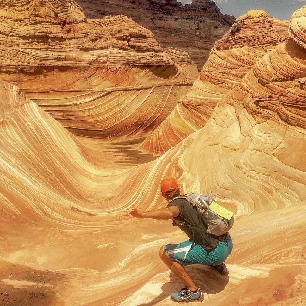 Man pretending to surf the red sandstone wave formation in Arizona