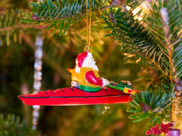 christmas ornament hangs on tree with santa in a kayak