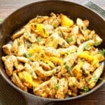 cast iron skillet of pan-fried moroccan chicken on wood table