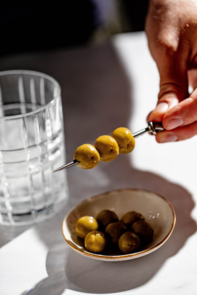 Olives being picked up to garnish the martini. 