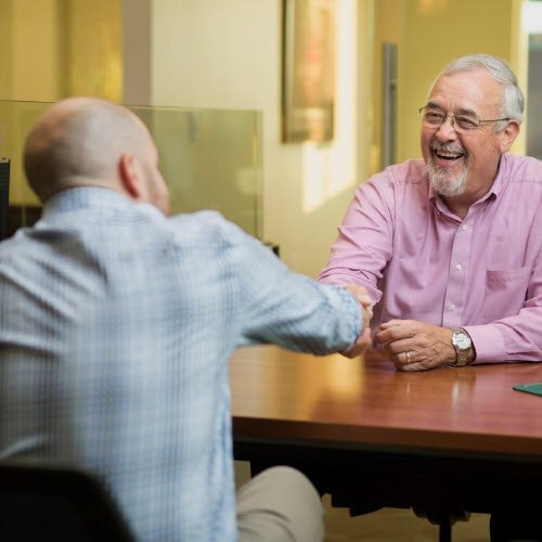 Banker shaking hands over a desk with customer