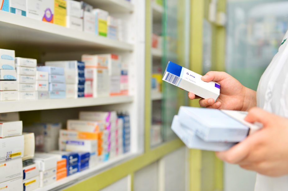 Pharmacist holding medicine box in pharmacy drugstore.