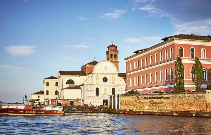 Daytime hotel exterior with boat at the San Clemente Palace Kempinski in Venice, Italy.