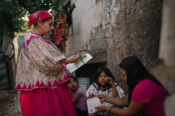 Julia Paredes Lopez, a nurse with the Chihuahua Health Secretariat, reviews the vaccination card of Argelia at an indigenous camp in Chihuahua City, Mexico, on 24 June 2024. For 30 years, nurse Julia Paredes has traveled distances on horseback or by foot to vaccinate remote villages, overcoming linguistic and cultural barriers to provide the preventive care.  "In the last 30 years, I've seen how the vaccines arrived to the most remote localities. I've seen how people stopped dying because of measles. I would like to be remembered with a vaccine thermos in the streets, talking to people and telling them that vaccines save lives," she said.