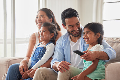 Young family looking safe and content while watching tv peacefully together on a sofa at home