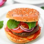 pumpkin burgers on a white plate - black bean pumpkin burgers topped with spinach, tomato, cheese, onions, ketchup