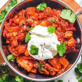 chana masala served in a silver bowl with yogurt and cilantro