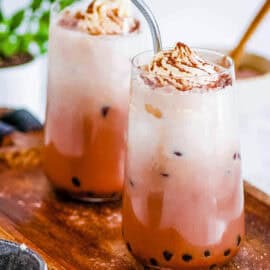 Chocolate milk tea served in two glasses topped with whipped cream.