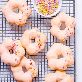 Baked mochi donuts with vegan glaze and sprinkles on a wire rack.