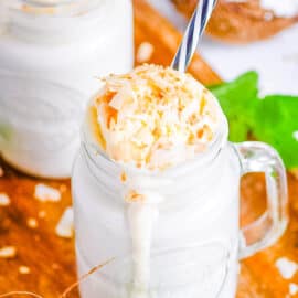 Easy coconut milkshake poured into mason jar glasses, topped with ice cream and coconut shavings.