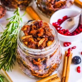 Vegan mincemeat in glass jars with holiday decorations surrounding the jars.