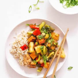 Vegan sweet and sour tofu, served on a white plate with chopsticks.