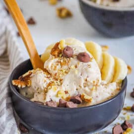 Easy chocolate banana ice cream served in a black bowl, topped with chocolate chips and banana slices.