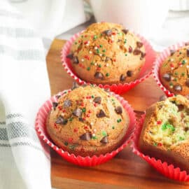 Christmas muffins with chocolate chips on a wooden cutting board.