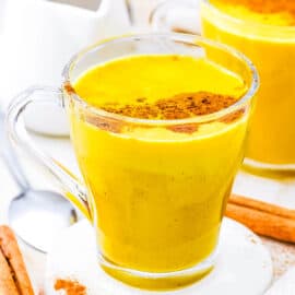 Golden turmeric milk latte, served in a glass, topped with cinnamon.