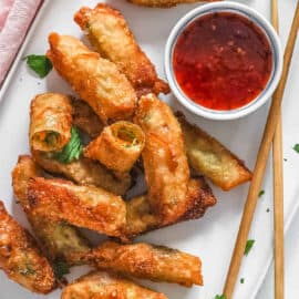 Easy vegan egg rolls served on a white plate with a dipping sauce on the side.