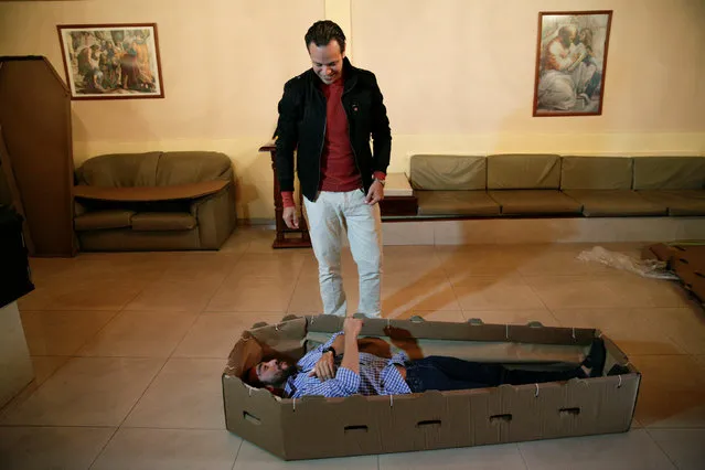 Elio Angulo (bottom C) lies inside a cardboard coffin next to Alejandro Blanchard as they introduce their product to potential customers at a mortuary in Valencia, in the state of Carabobo, Venezuela August 25, 2016. (Photo by Marco Bello/Reuters)