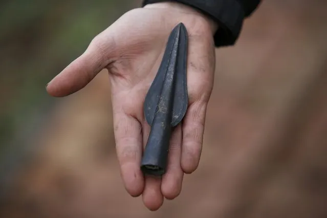 An arrow-head discovered in 2006 by Archaeologists of the University of Cambridge Archaeological Unit, is displayed by one of the team uncovering Bronze Age wooden houses, preserved in silt, from a quarry near Peterborough, Britain, January 12, 2016. (Photo by Peter Nicholls/Reuters)