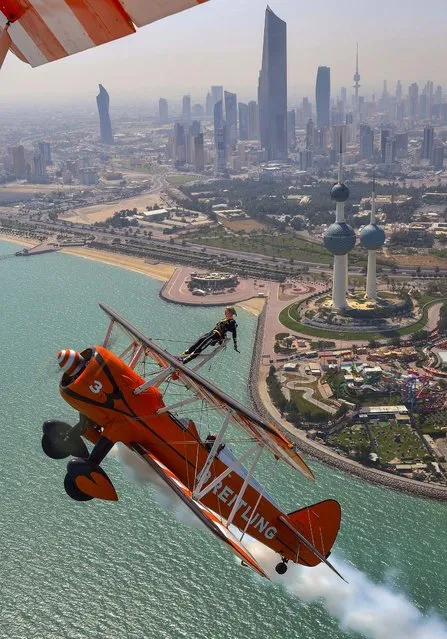 Breitling Wingwalker Freya Paterson, from Liverpool, UK, flies above Kuwait City's iconic Water Towers with pilots David Barrell and Martyn Carrington, on March 6, 2014. The team loop and roll up to 160 mph enduring G-forces of 4-5g. (Photo by Katsuhiko Tokunaga/Breitling)