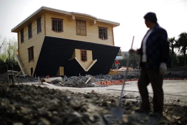 A labourer takes a break as she works at an upside-down house under construction at Fengjing Ancient Town, Jinshan District, south of Shanghai, March 17, 2014. (Photo by Carlos Barria/Reuters)