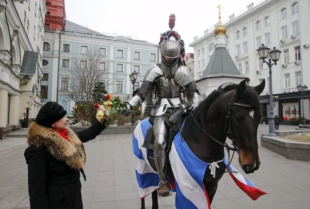 A participant, riding a horse and dressed as a knight, presents flowers to women during an event marking Valentine's Day in central Moscow, Russia, February 14, 2016. (Photo by Maxim Zmeyev/Reuters)