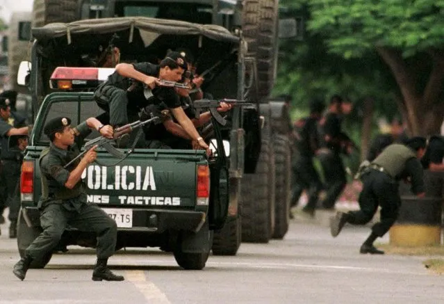 Elite special police run for cover after gunfire was heard from inside the Japanese ambassador's residence in Lima, Peru, January 27, 1997. At the moment the shots were fired, police were parading past the residence in a show of force, and helicopters were flying above. Earlier, several armored personnel carriers rolled past the compound. Tupac Amaru rebels had seized the diplomatic compound December 17 and held 72 hostages. (Photo by Andrew Winning/Reuters)