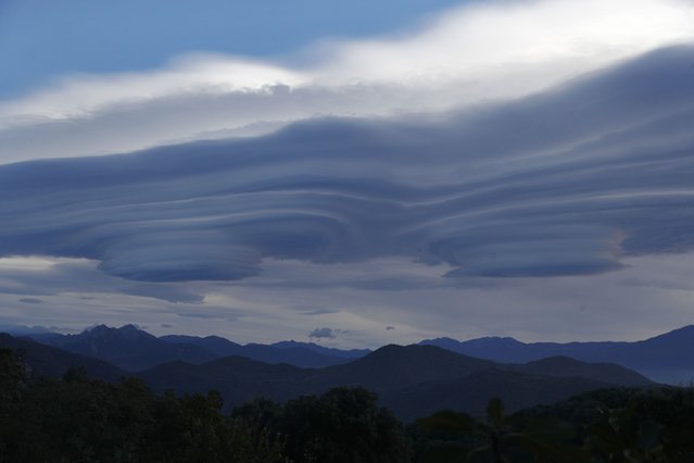 This photograph, taken in Cognocoli-Monticchi on the French Mediterranean island of Corsica on November 14, 2023 shows lenticular clouds above Corsican mountains. (Photo by Pascal Pochard-Casabianca/AFP Photo)