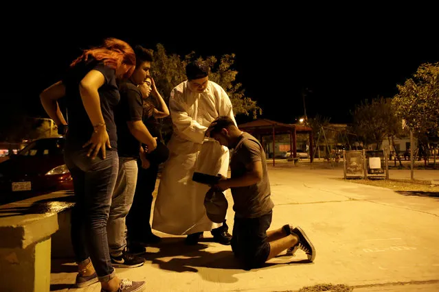 An aspiring Catholic priest Jose Luis Guerra, a member of Raza Nueva in Christ, a project of the archdiocese of Monterrey, and other missionaries hand out a Bible to Angel Castillo, who wants to become a missionary with Raza Nueva, in the municipality of Garcia, outskirts of Monterrey, Mexico, July 12, 2016. (Photo by Daniel Becerril/Reuters)