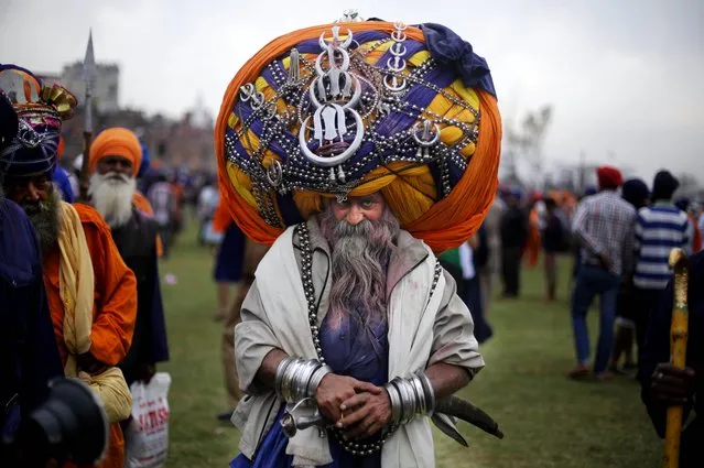 A Sikh warrior, wearing a huge turban attends the annual fair of “Hola Mohalla” in Anandpur Sahib, in the northern Indian state of Punjab, Monday, March 17, 2014. Believers from various parts of northern India collect at the religious fair to celebrate the festival of Holi in a tradition set by the tenth Sikh guru Guru Gobind Singh in the seventeenth century. Nihangs, or Sikh warriors, display their martial skills and attire during the fair, believed to be maintained in the exact tradition as set by the Guru. (Photo by Altaf Qadri/AP Photo)