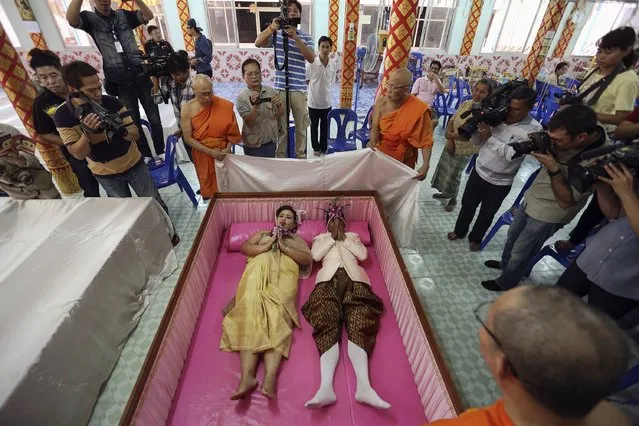 People take pictures and Buddhist monk chants as a groom and a bride lay inside a pink coffin during their wedding ceremony at Wat Takien temple in Nonthaburi province, on the outskirts of Bangkok February 14, 2015. (Photo by Damir Sagolj/Reuters)