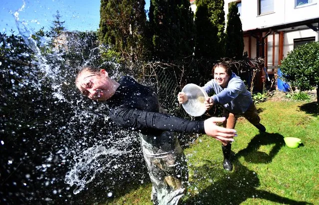 Polish boys and girls throw water over each other on “Smigus-dyngus” (or Wet Monday) during the Easter Monday in Szczecin, northwestern Poland, 18 April 2022. Smigus-dyngus is a Roman Catholic celebration held on Easter Monday in Poland. Traditionally, boys throw water over girls, this is accompanied by a number of other rituals, such as making verse declarations and holding door-to-door processions. (Photo by Marcin Bielecki/EPA/EFE)