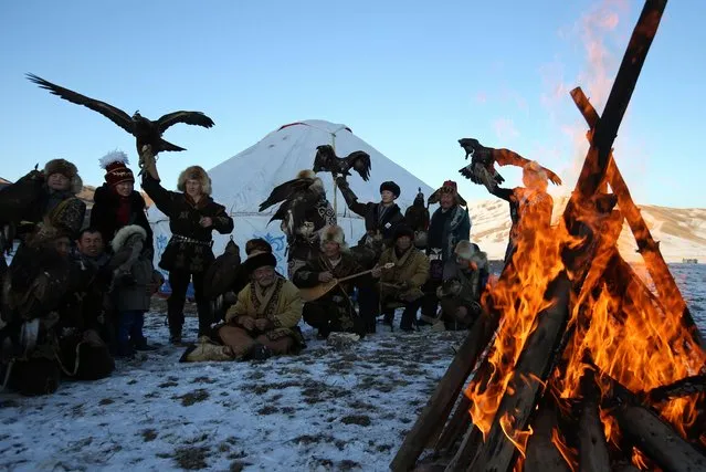 Hunters with their tamed golden eagles and hawks gather around a bonfire during a traditional hunting contest outside the village of Kaynar in Almaty region, Kazakhstan on December 8, 2019. (Photo by Pavel Mikheyev/Reuters)