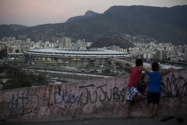 Two boys look out from the Mangueira slum towards the Maracana Stadium that is hosting the Rio's 2016 Summer Olympics opening ceremonies, in Rio de Janeiro, Brazil, Friday, August 5, 2016. (Photo by Leo Correa/AP Photo)