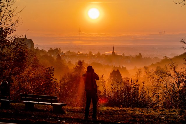 A photographer takes pictures as the sun rises over the city of Kronberg near Frankfurt, Germany, Monday, November 4, 2024. (Photo by Michael Probst/AP Photo)