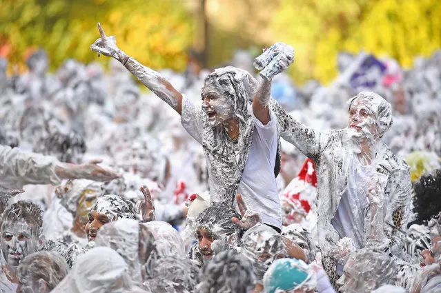 Students from St Andrew's University indulge in a tradition of covering themselves with foam to honour the “academic family” on October 20, 2014, in St Andrews, Scotland. Every November the “raisin weekend” which is held in the university's Lower College Lawn, is celebrated and a gift of raisins (now foam) is traditionally given by first year students to their elders as a thank you for their guidance and in exchange they receive a receipt in Latin. (Photo by Jeff J. Mitchell/Getty Images)