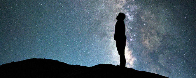 a figure silhouetted against the Milky Way galaxy