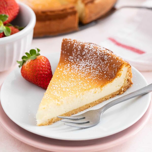 A slice of cheesecake on a white plate with a fork next to it.