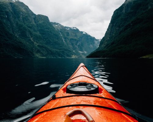 Orange kayak on a river in a valley