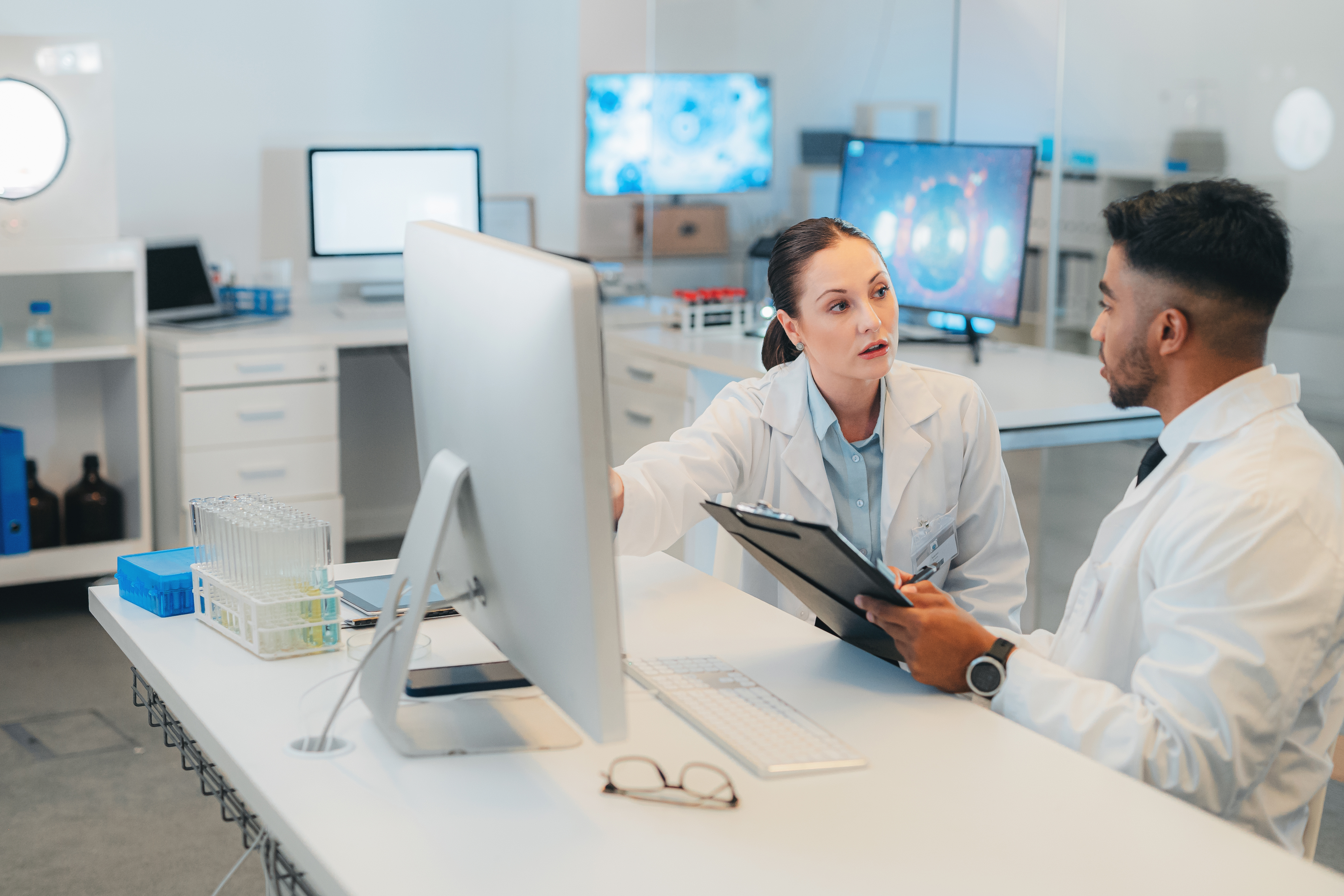 Two health care providers sitting talking at a desk. 