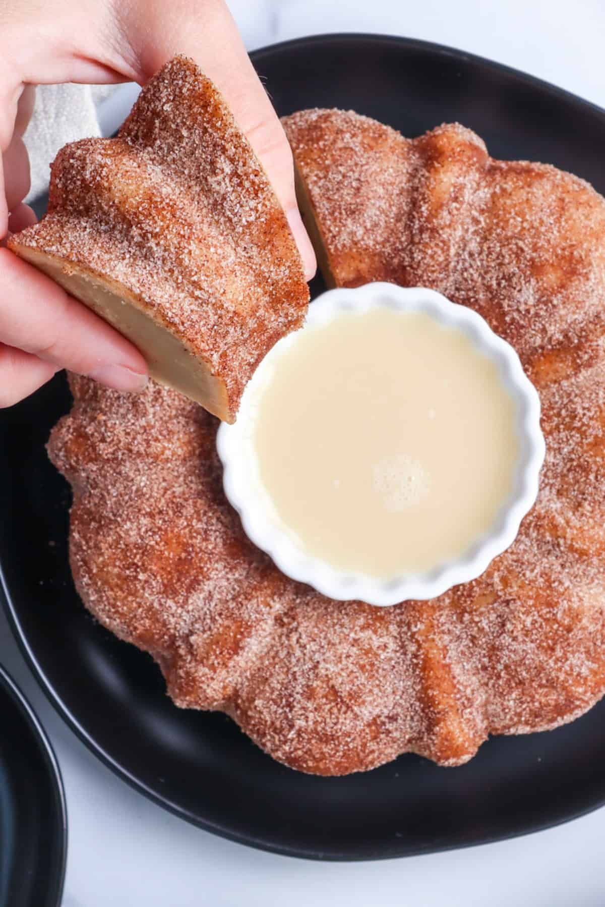 a hand holding a piece of Apple Cider Doughnut Cake