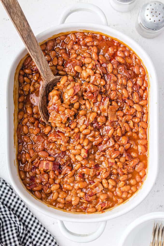 baked beans being scooped out using wooden spoon