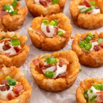 a couple of loaded tater tot cups on top of parchment paper.