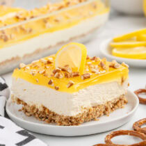 Slice of lemon pretzel dessert topped with crushed pretzels and a lemon wedge.