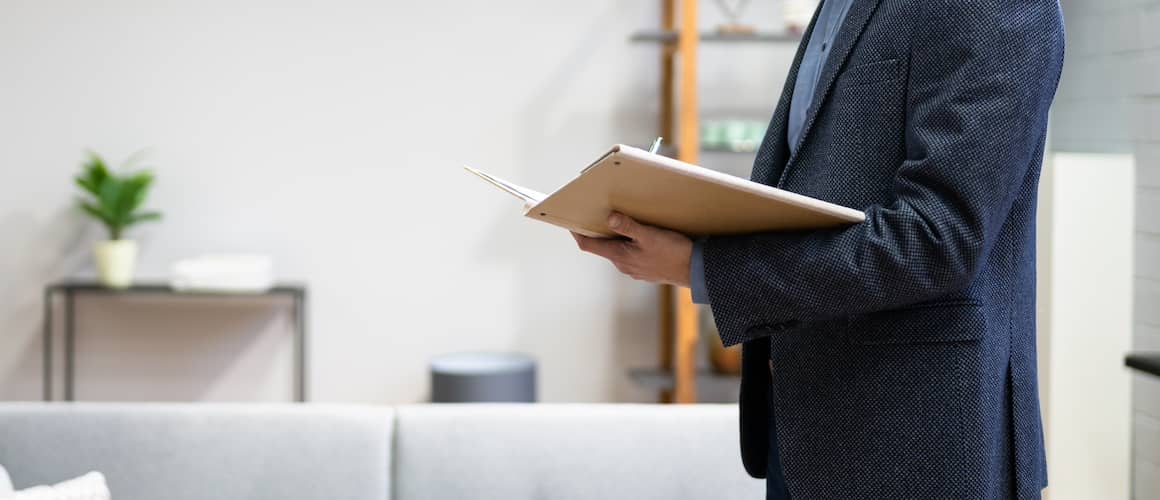 Man in suit taking notes during a full home appraisal.