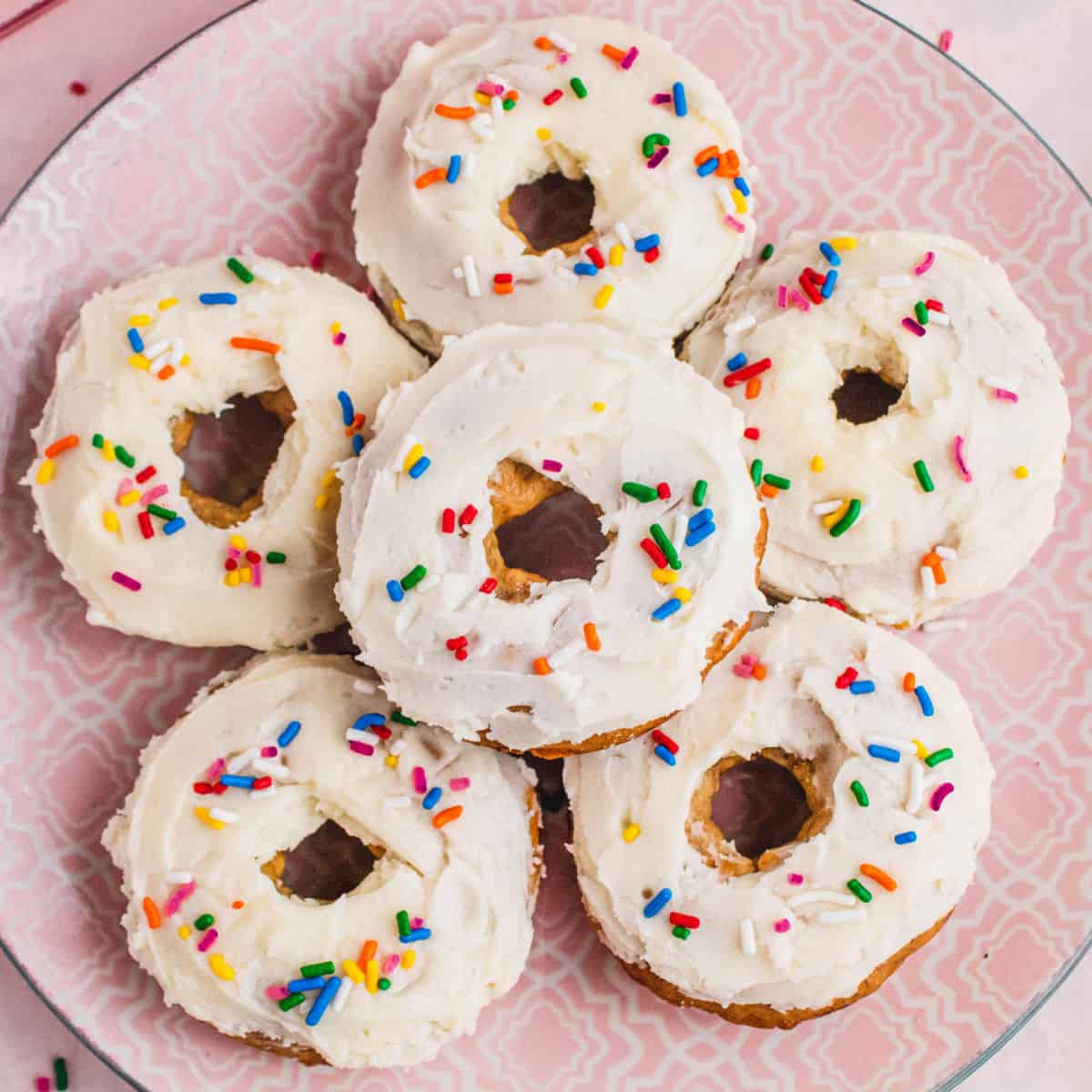 looking down at a plate of banana donuts with cream cheese frosting