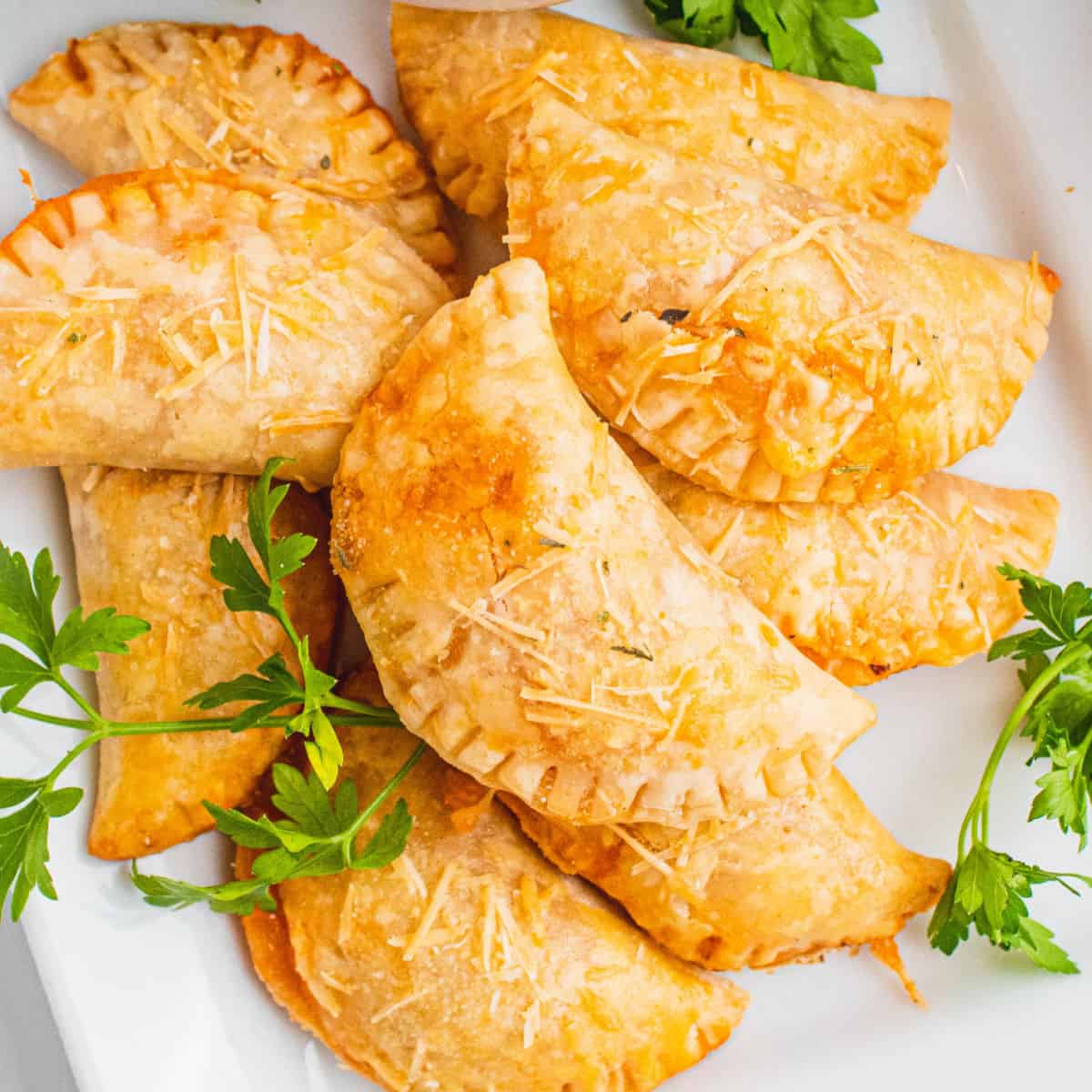 square image of pepperoni pizza bites on a plate with fresh parsley sprigs