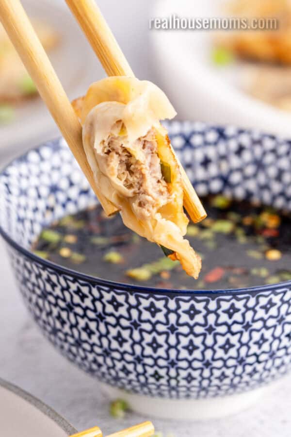 close up of a potsticker with a bite taken to show the filling