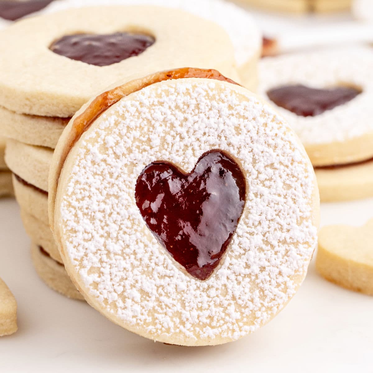 square image of a strawberry sandwich cookie leaning against a stack of sandwich cookies