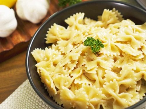 buttery-garlic-bow-tie-pasta-recipe firm and tender bow tie or farfalle pasta noodles with garlic butter sauce with a squeeze of lemon and garnished with parsley